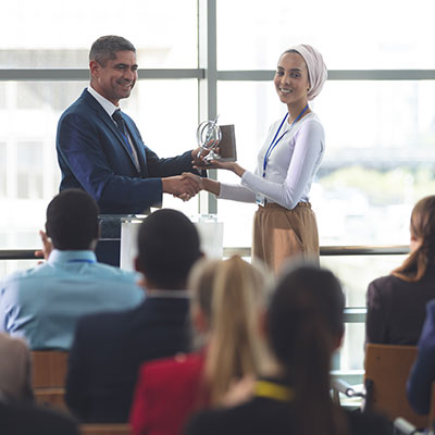 Woman receiving a recognition trophy from her boss in front of the entire company.